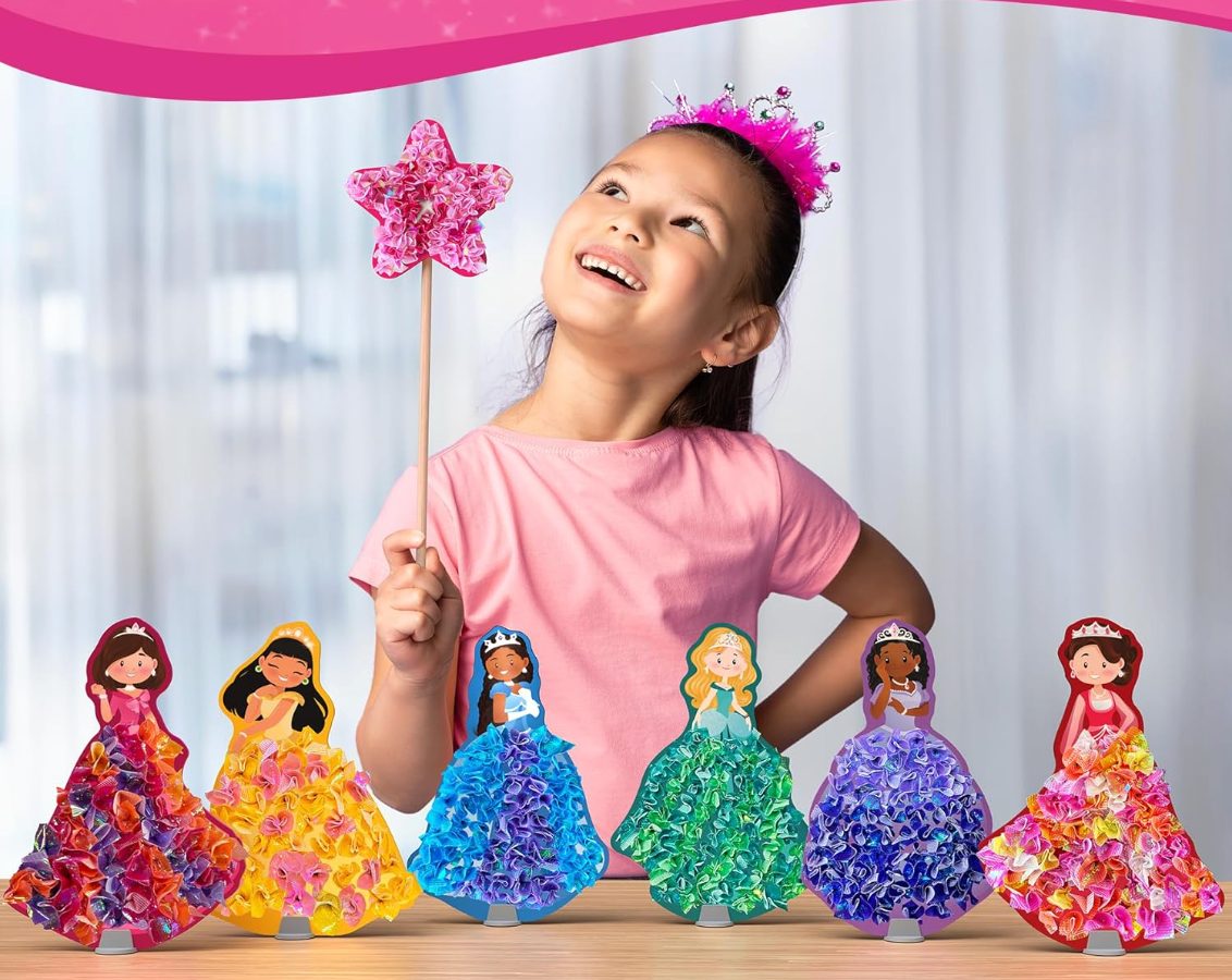 Young girl holding a star wand smiling behind six colorful foam princess crafts with fabric gowns on a table