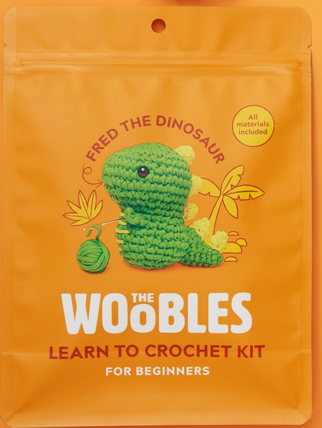 Orange package featuring Fred the Dinosaur crochet kit with green crochet dinosaur and yarn ball illustration