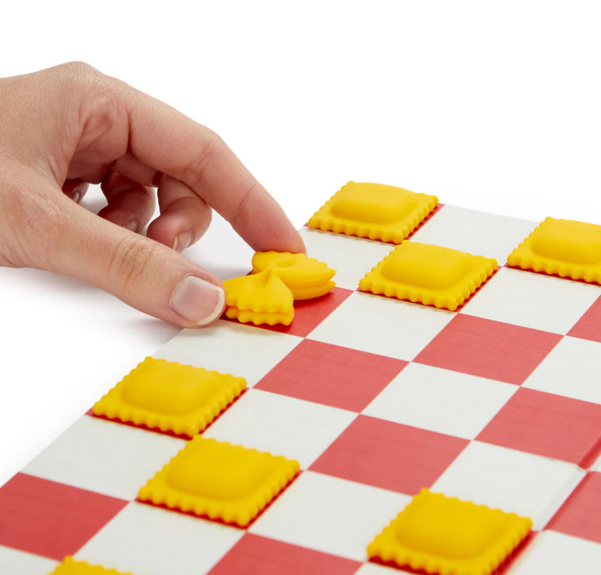Hand moving a yellow pasta-shaped game piece on a red and white checkered board for a pasta checkers game