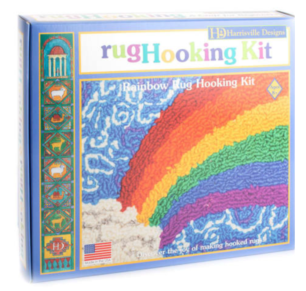 Box of rug hooking kit featuring a colorful rainbow design with blue sky and white clouds on the front panel