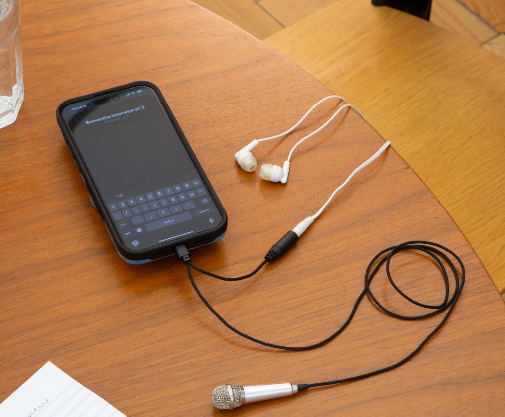 Plug and Play Mini Microphone connected to a smartphone on a wooden table, ready for recording or podcasting.