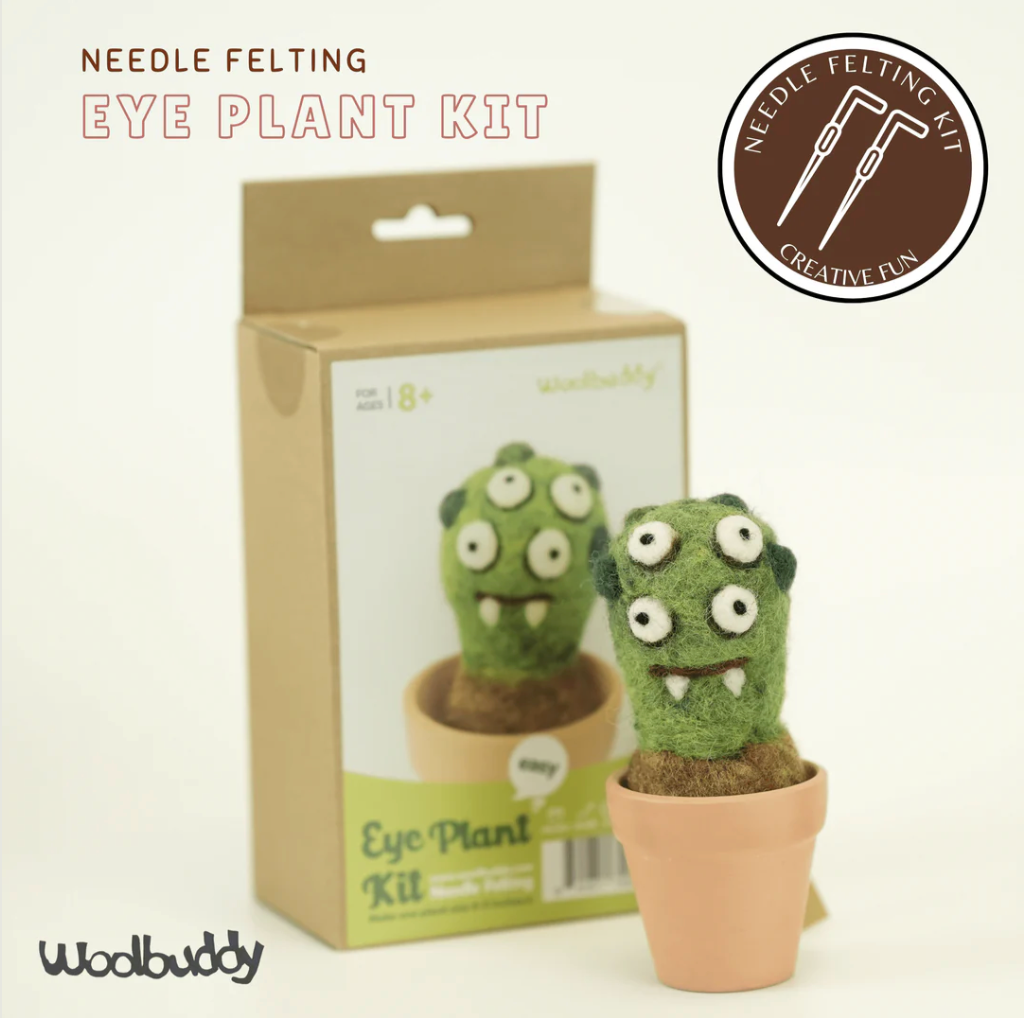 Green felted eye plant monster with multiple eyes in a small terracotta pot next to its packaging box
