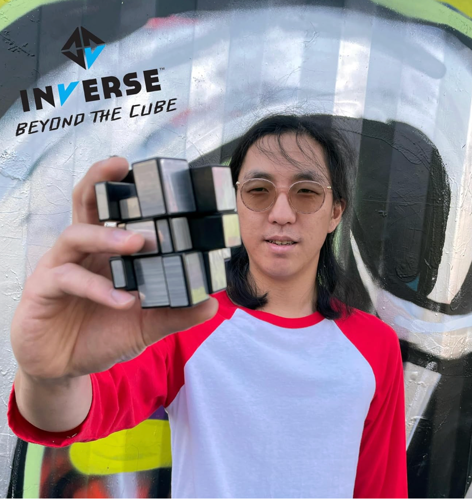 Person holding a Reflectron Mirror Puzzle Cube with a shiny surface and irregular, shifting segments against a colorful wall background