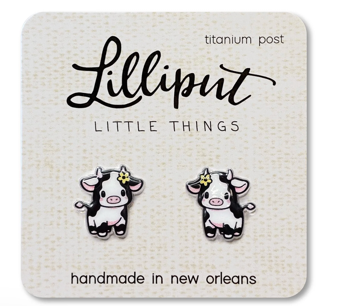 Cute baby cow stud earrings with titanium posts on a card, designed for sensitive ears and waterproof wear