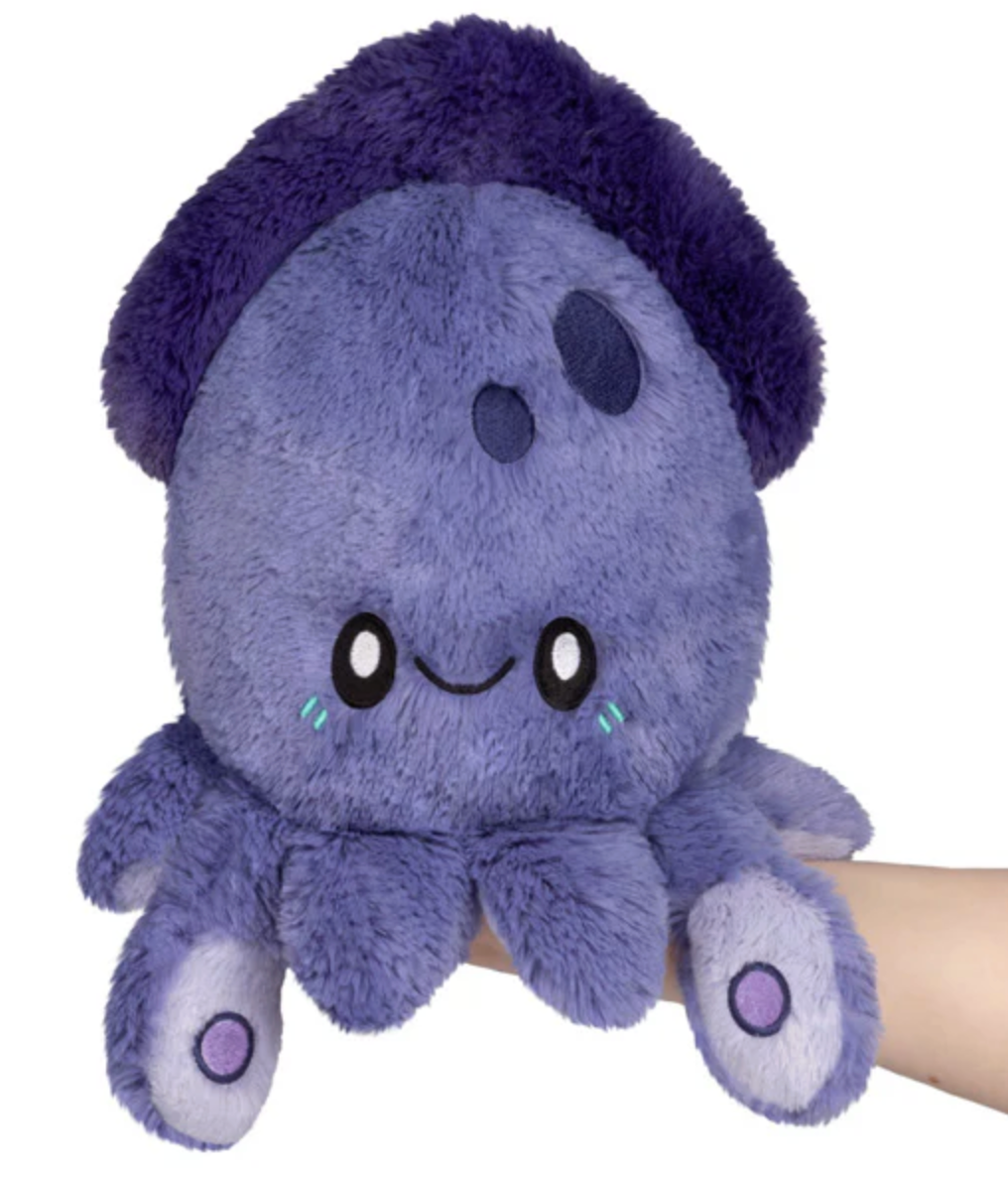 Soft plush toy in shades of purple shaped like a smiling octopus with large eyes and small decorative spots