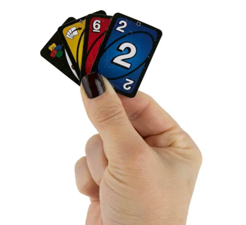 World's Smallest Uno No Mercy cards held in a hand with colorful game cards visible