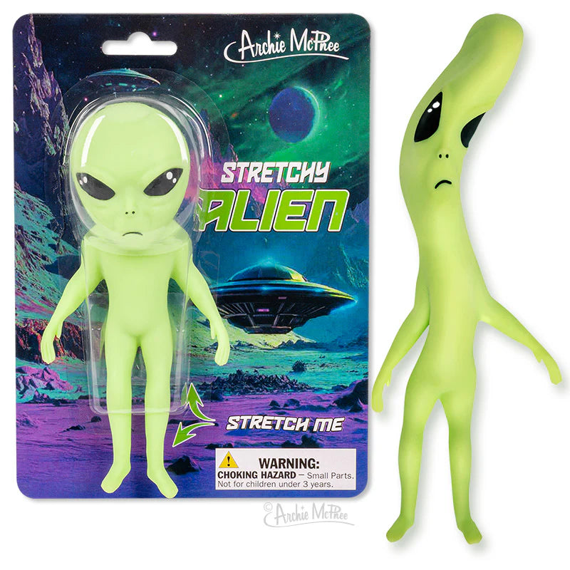 Green stretchy alien toy with large black eyes and thin limbs in outer space packaging background