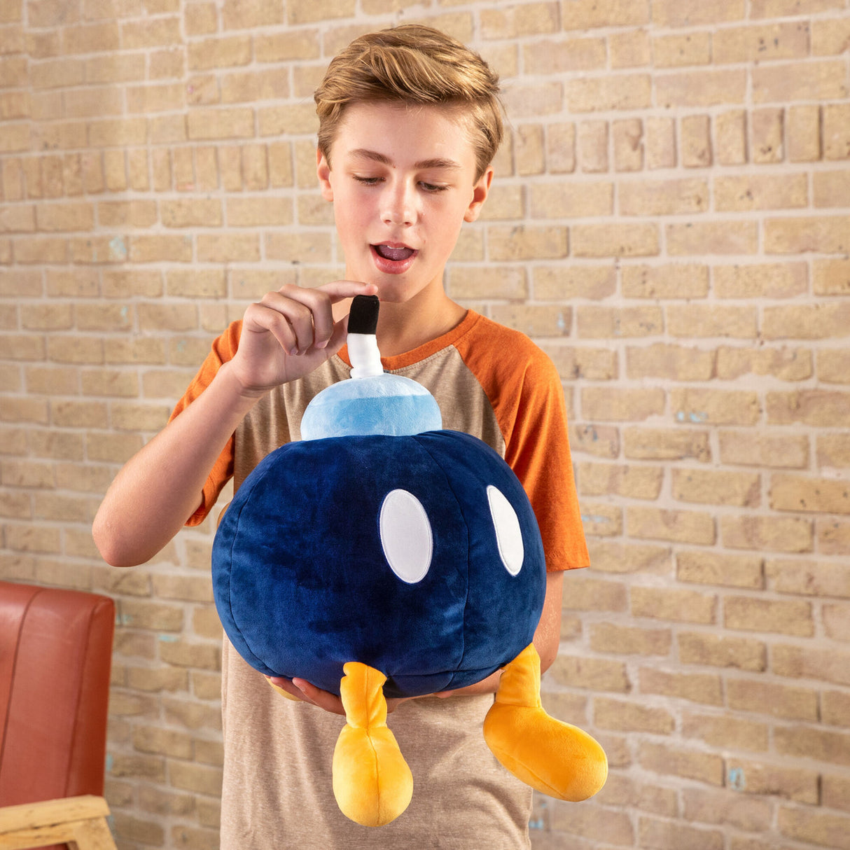 Boy holding a soft, squishy Super Mario Bob-Omb plush with yellow feet and a white fuse, 15 inches tall.