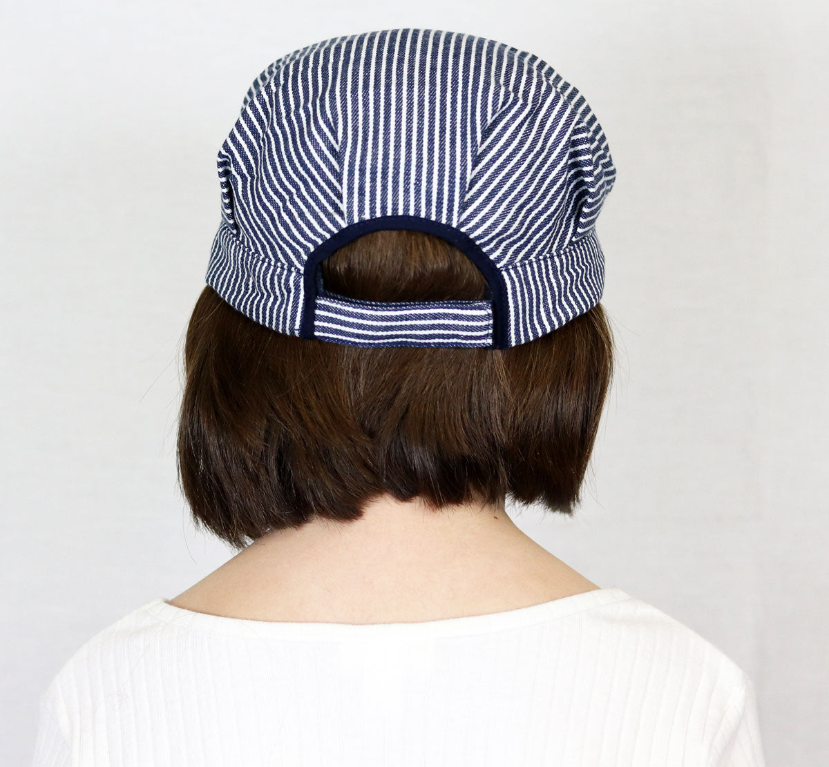 Back view of child wearing a striped Train Engineer Cap with adjustable strap for comfortable fit.