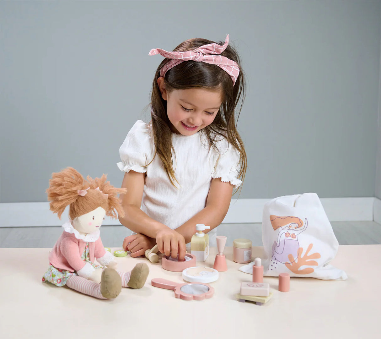 Young girl playing with Spa Retreat Set including spa accessories and drawstring bag with mermaid illustration.