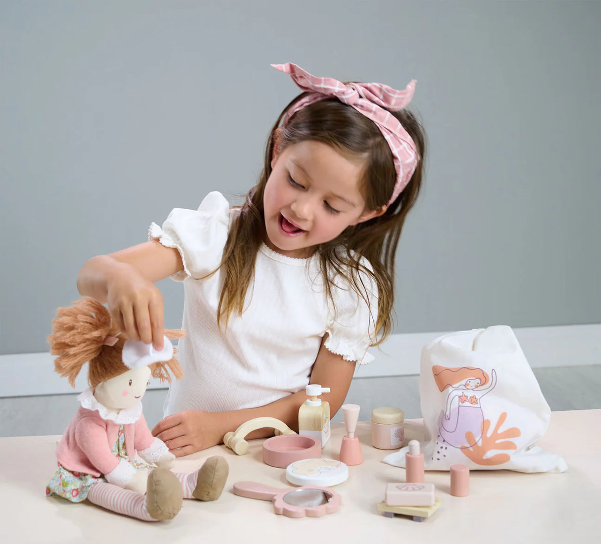 Young girl playing with the Spa Retreat Set including beauty accessories and a mermaid drawstring bag.