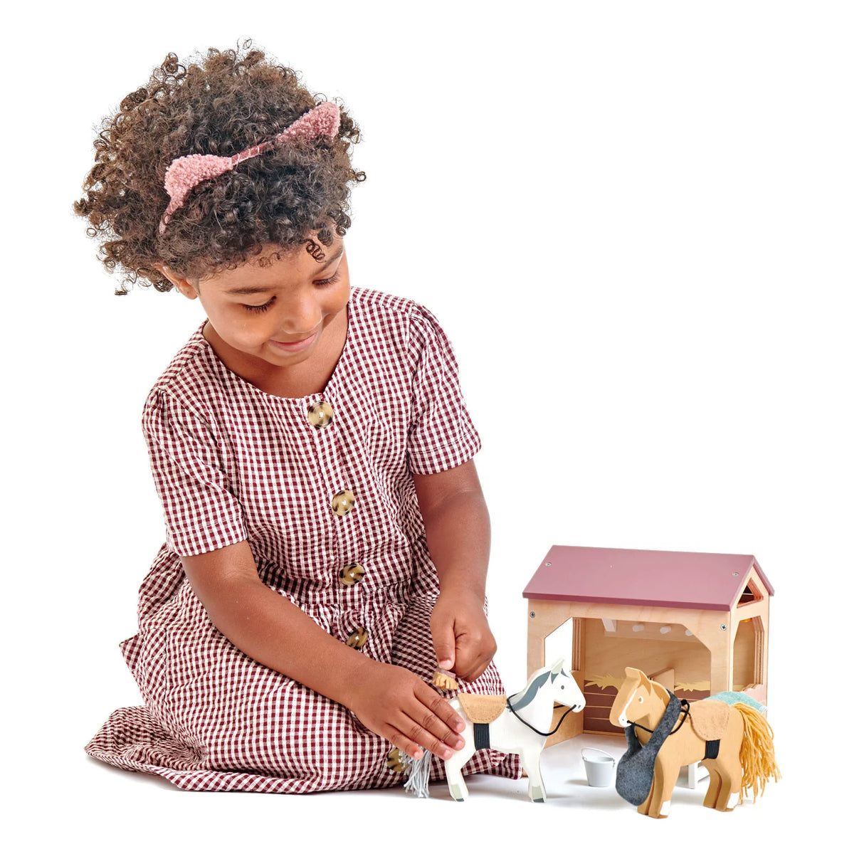Child playing with The Stables toy set featuring ponies, stable, brush, and accessories for imaginative grooming play.