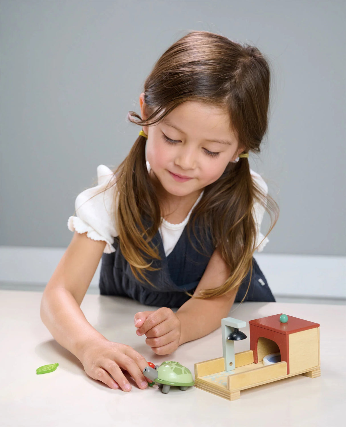 Young girl playing with the Tortoise Pet Set featuring wooden tortoises, cozy home, and playful accessories.