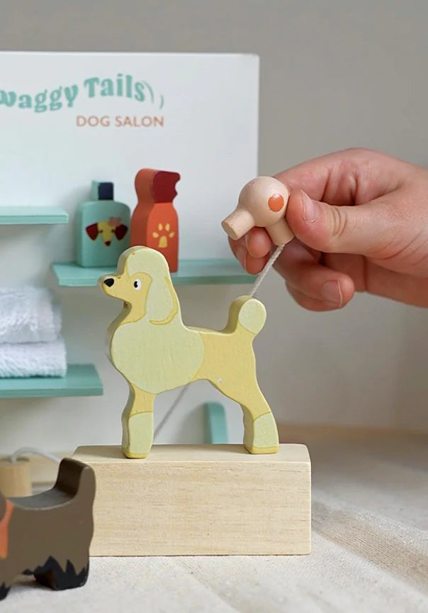 Hand holding hair dryer over wooden poodle in Waggy Tails Dog Salon grooming play set.