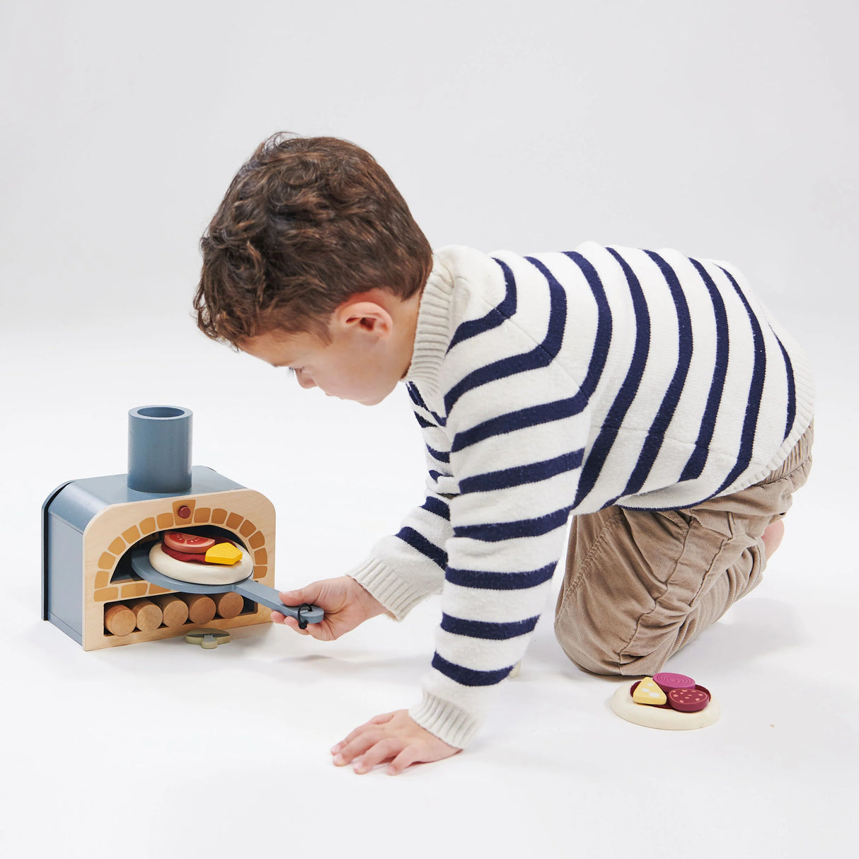 Child playing with a pretend pizza oven using pizza toppings and pizza slider in the Make Me a Pizza! toy set.