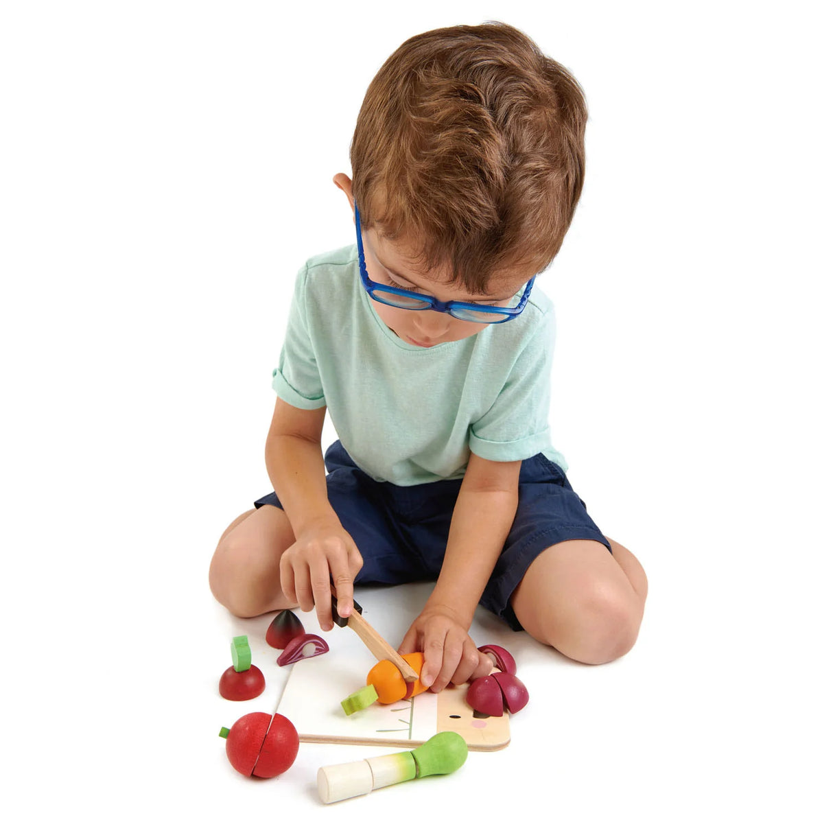 Child playing with Mini Chef Chopping Board set featuring wooden knife and vegetable pieces for imaginative play.