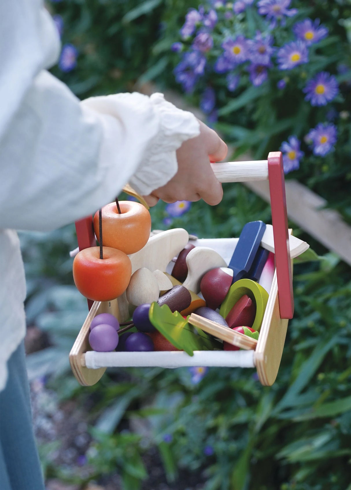 Child holding Wild Wood Foraging Trug filled with wooden foraged fruits, mushrooms, and flowers outdoors.
