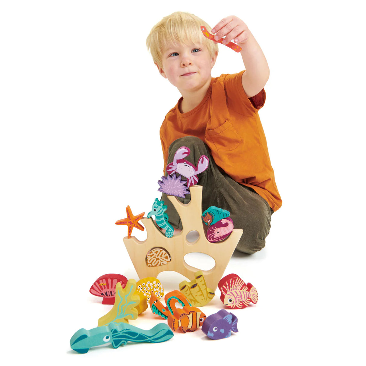 Child playing with colorful wooden sea creatures on Stacking Coral Reef toy with coral and marine animals pieces.