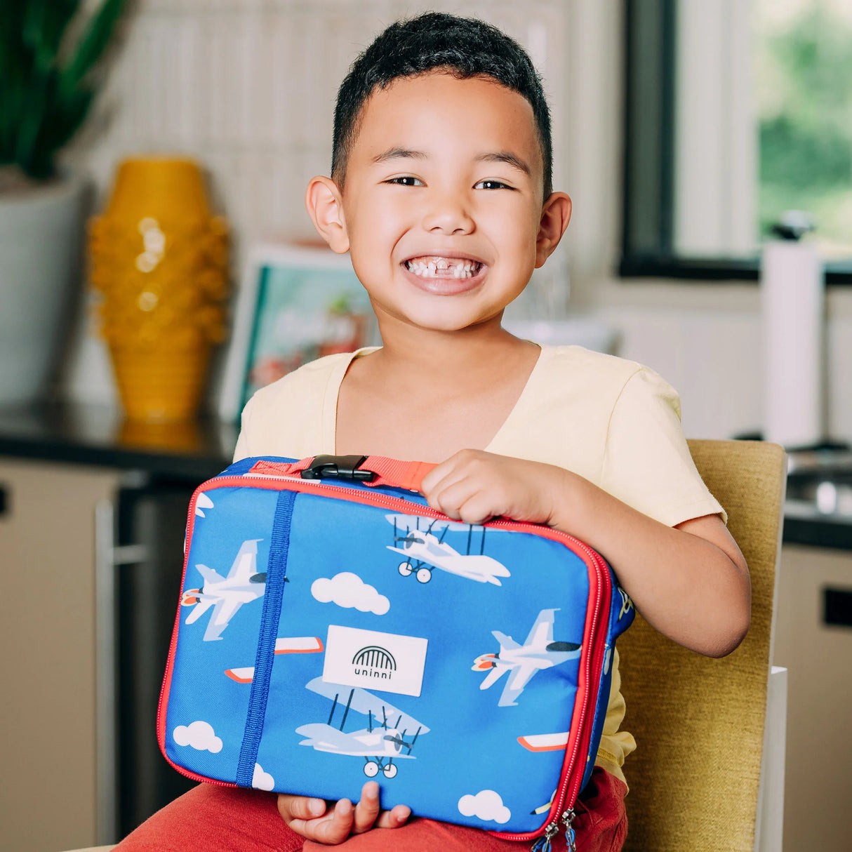 Smiling child holding the Lunch Bag | Airplane with airplane design and insulated compartments for organized meals.