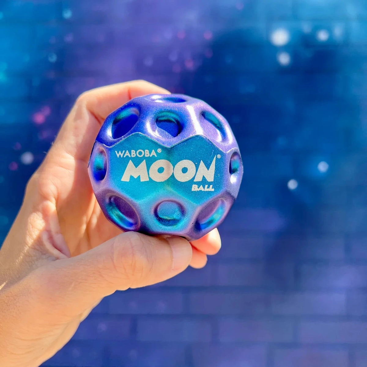 Moon Ball | Metallic | Metallic sensory ball held in hand against a blue background