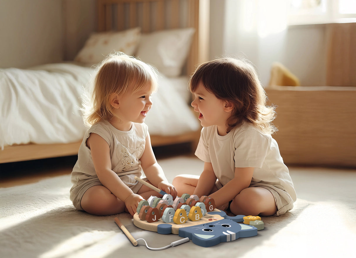 Two toddlers sitting on the floor playing with a colorful wooden alphabet fishing game together in a sunlit room