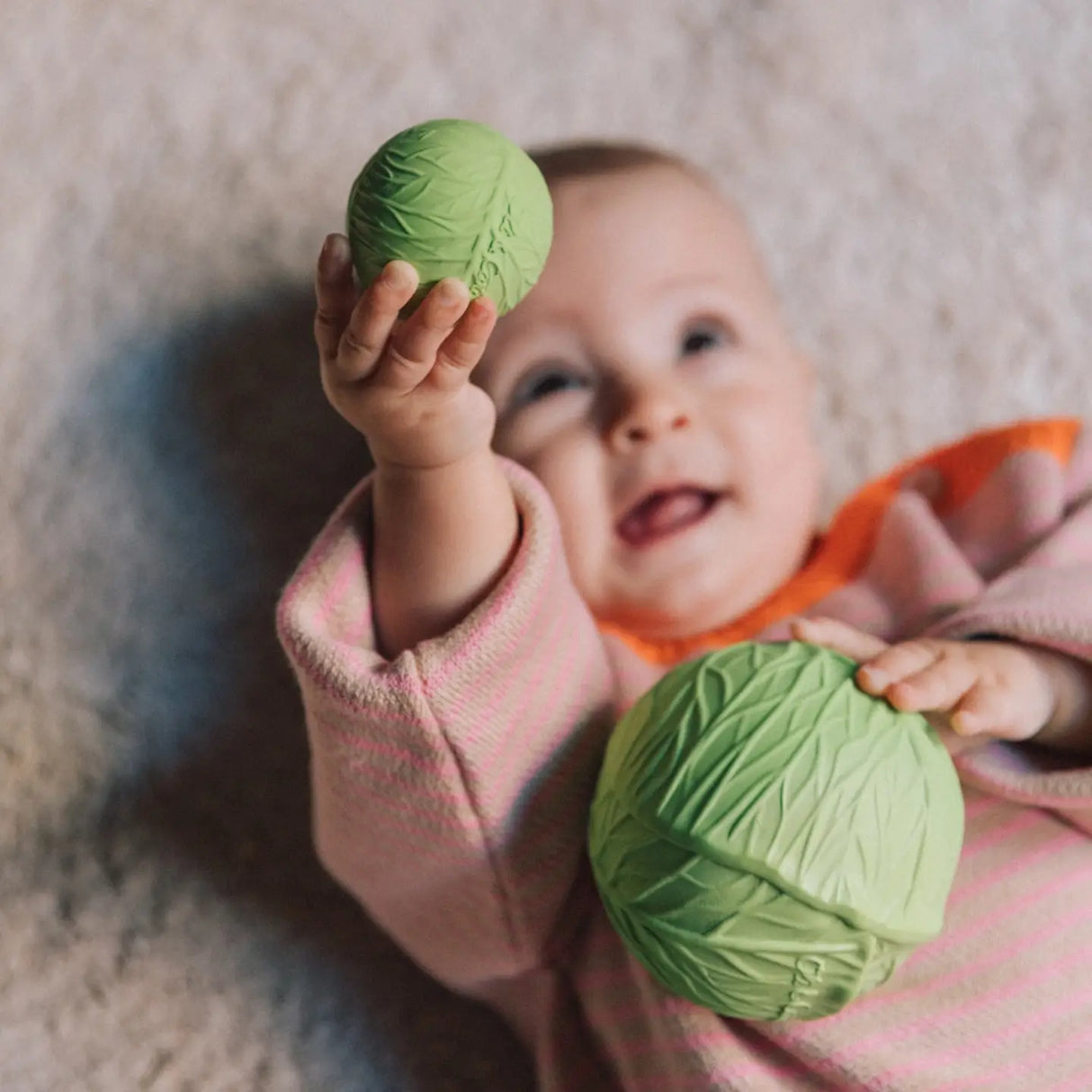 Baby holding soft green textured sensory balls designed for early development and soothing teething gums