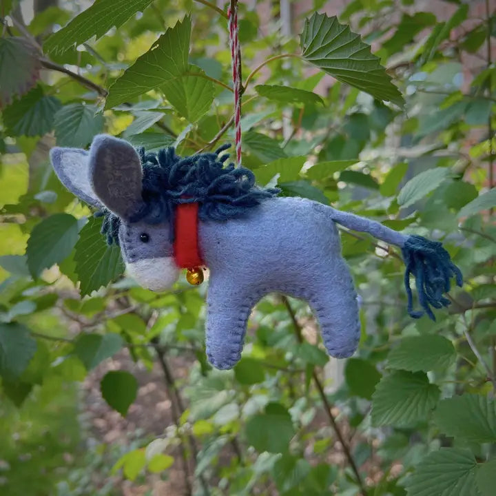 Donkey Felt Ornament handmade wool donkey with red collar and bell, hanging outdoors among green leaves.