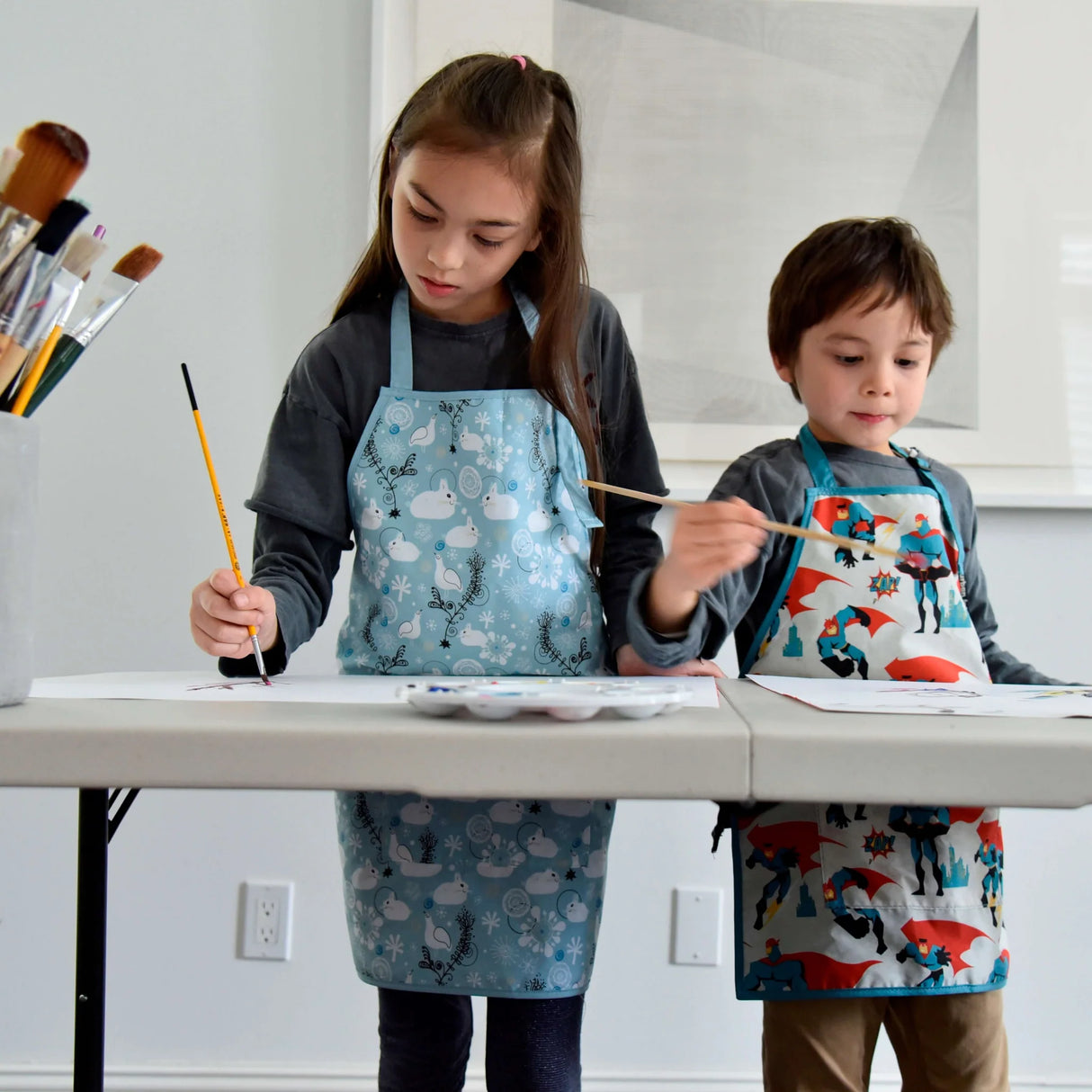 Children painting while wearing the Little Helper Apron | Balloons Small protecting clothes in a creative home setting.