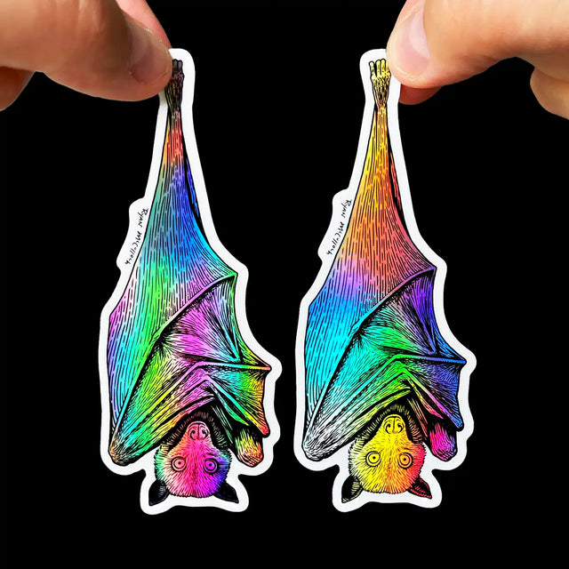 Hanging Bat Holographic Sticker held by two hands showing vibrant, waterproof, UV-protected bat art by Ryan McCulloch.