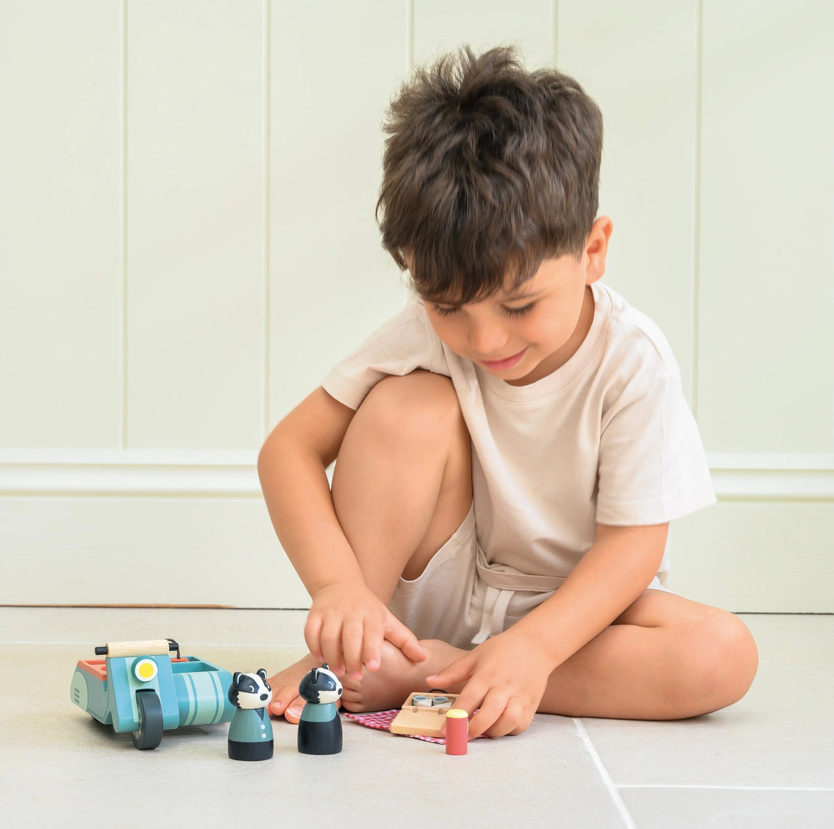 Badger Picnic Motorbike Ride toy with a child playing on the floor beside colorful figures and accessories