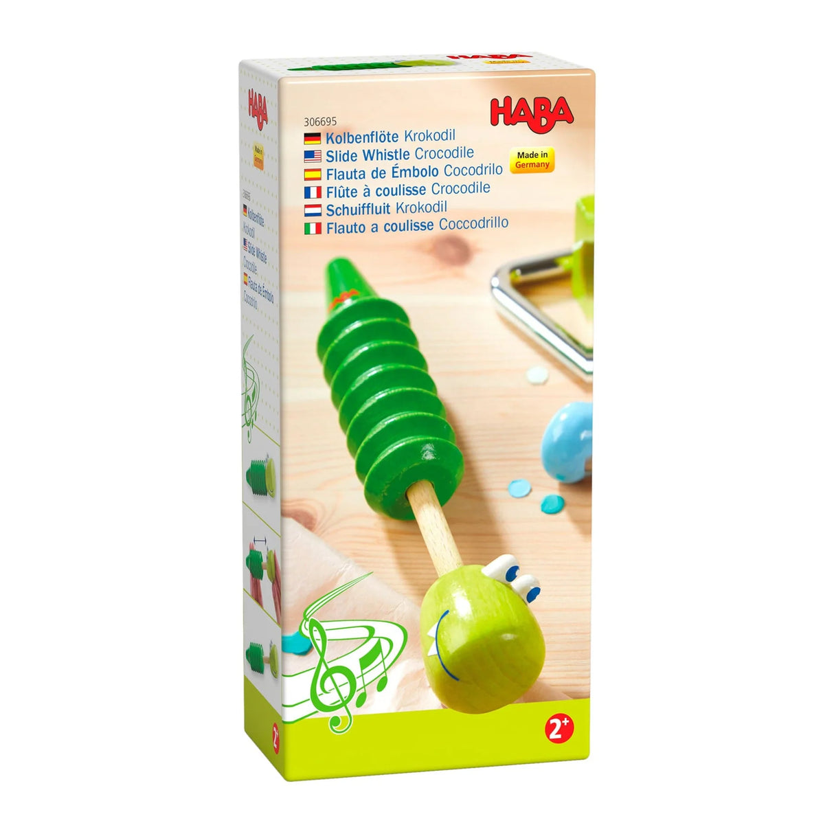 Green wooden slide whistle shaped like a smiling crocodile, designed for children aged two and up.