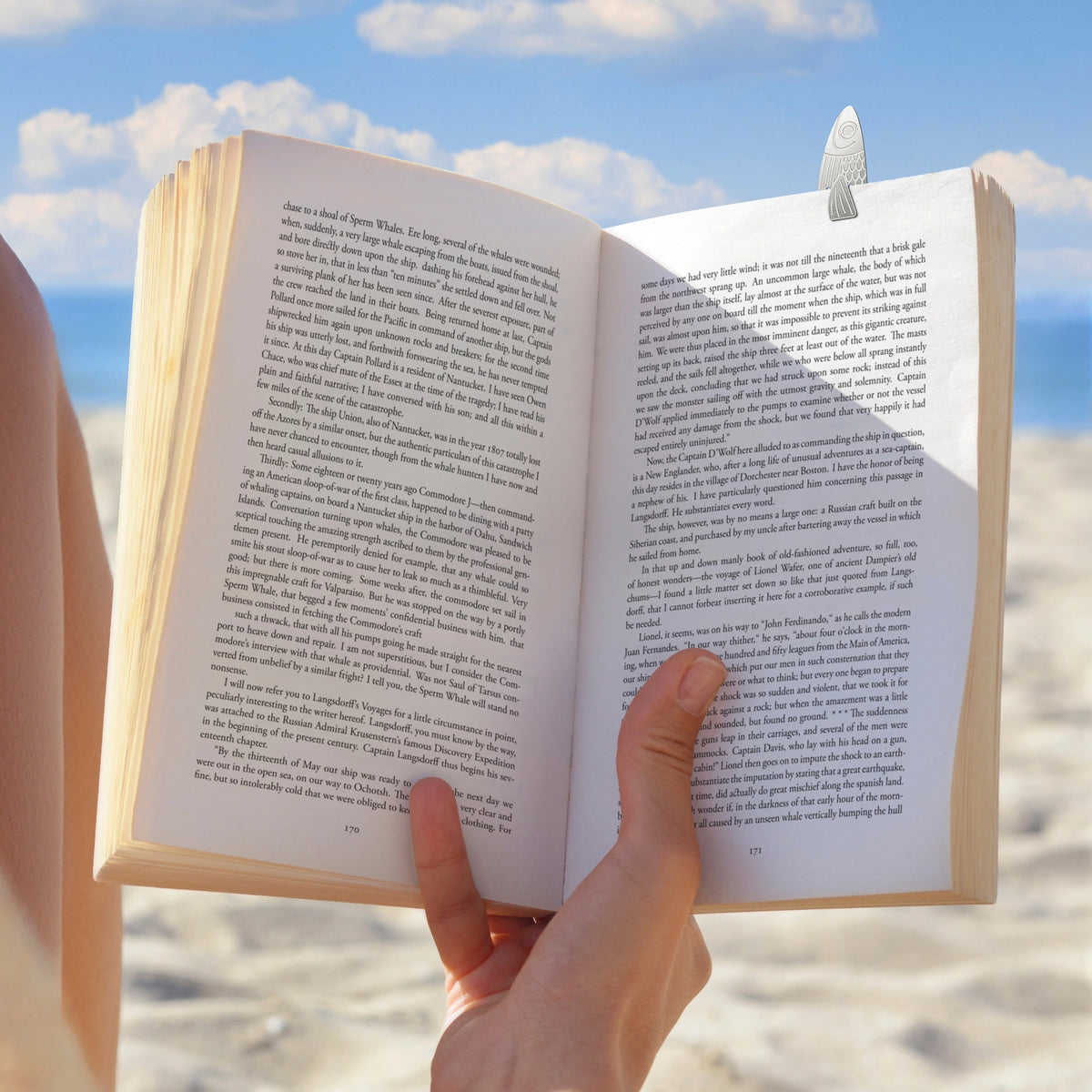 Water Marks Bookmarks featuring an open book with a feather bookmark by the beach
