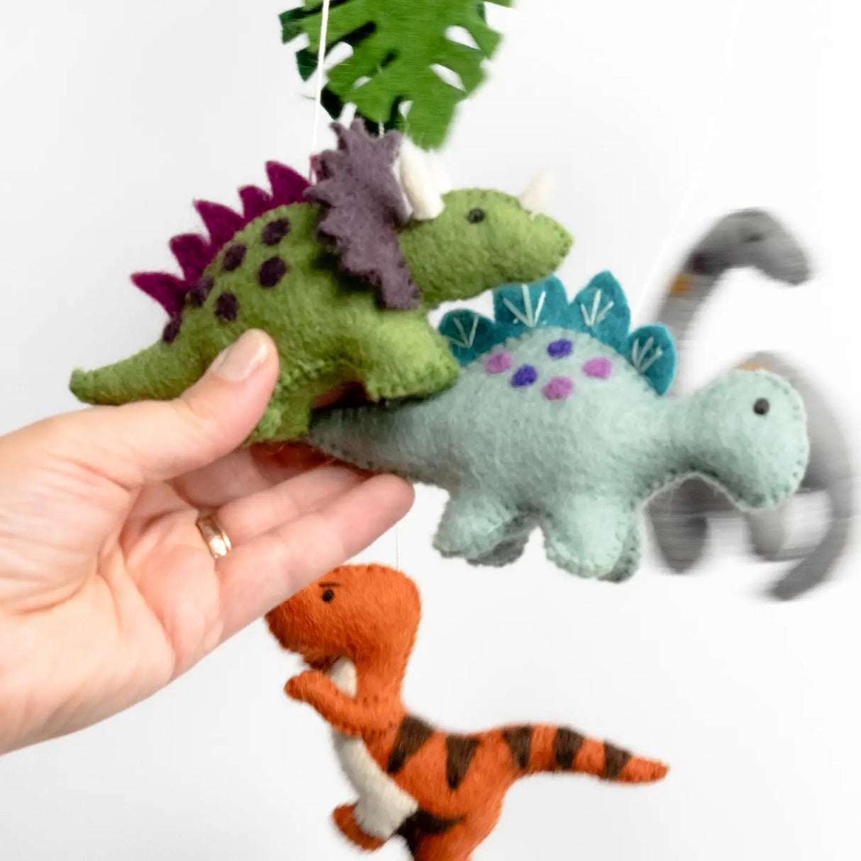 Felt Mobile | Baby Dinosaur with handmade colorful wool felt dinosaurs hanging gently over a crib nursery decor.