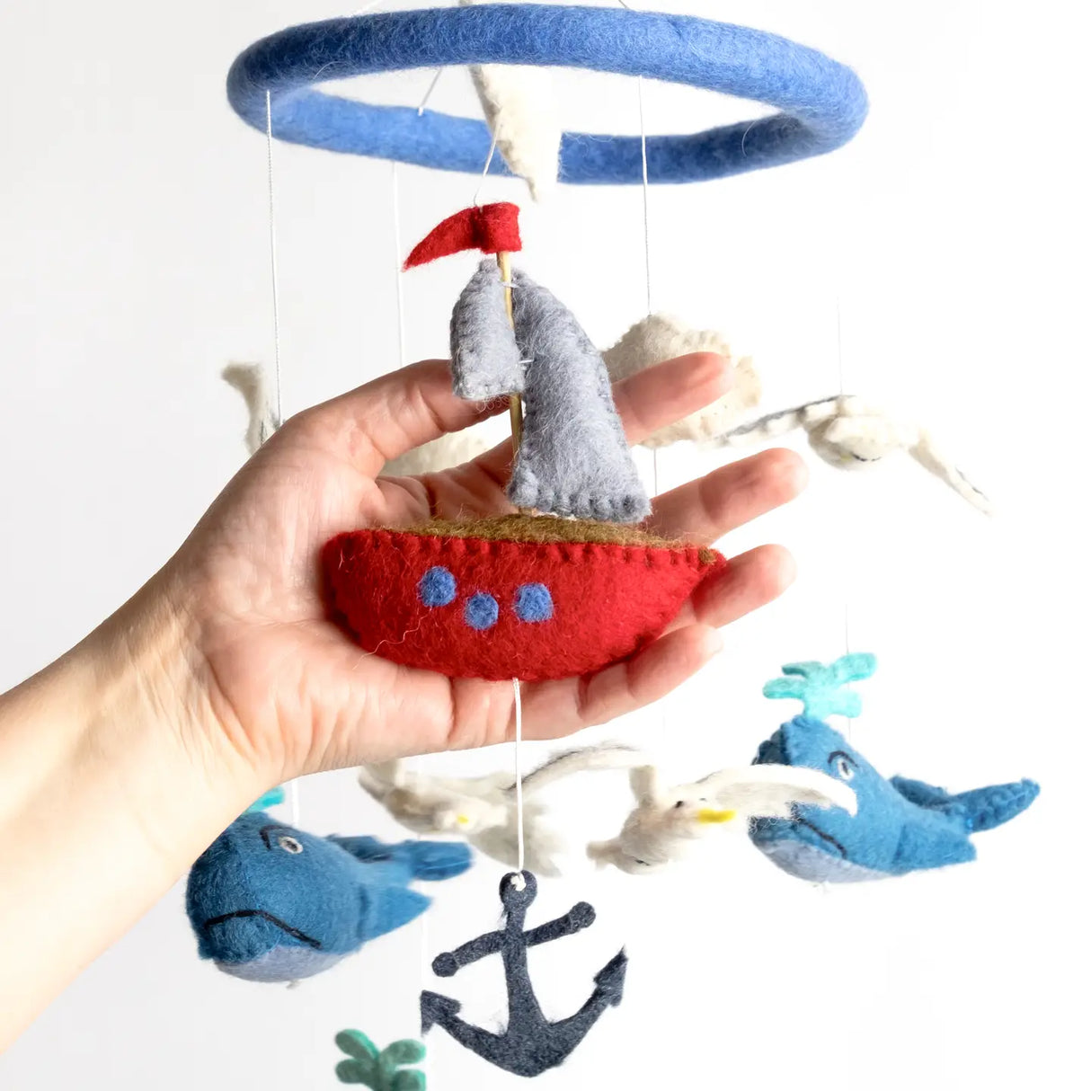 Felt Mobile | Whale & Sailboat showing handmade red sailboat, blue whales, and anchor hanging from blue felt hoop.
