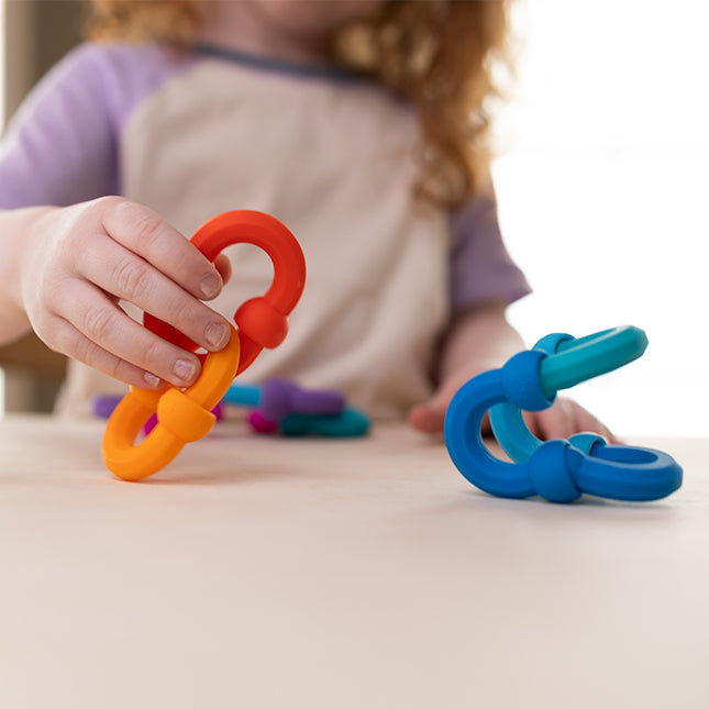Child playing with colorful silicone Plip Links, connecting pieces to encourage creativity and sensory play.