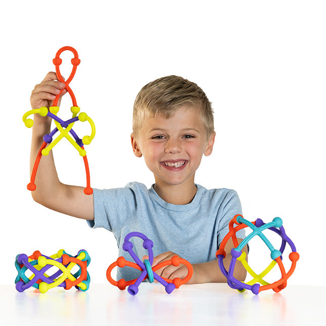 Happy child playing with colorful silicone pieces building creative shapes using the Plip Kit educational toy set.