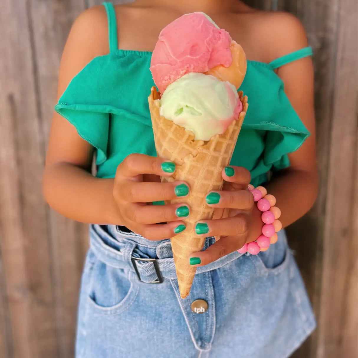 Close-up of a child holding ice cream cone with green nails painted using Nail Polish Ice Cream Dream.