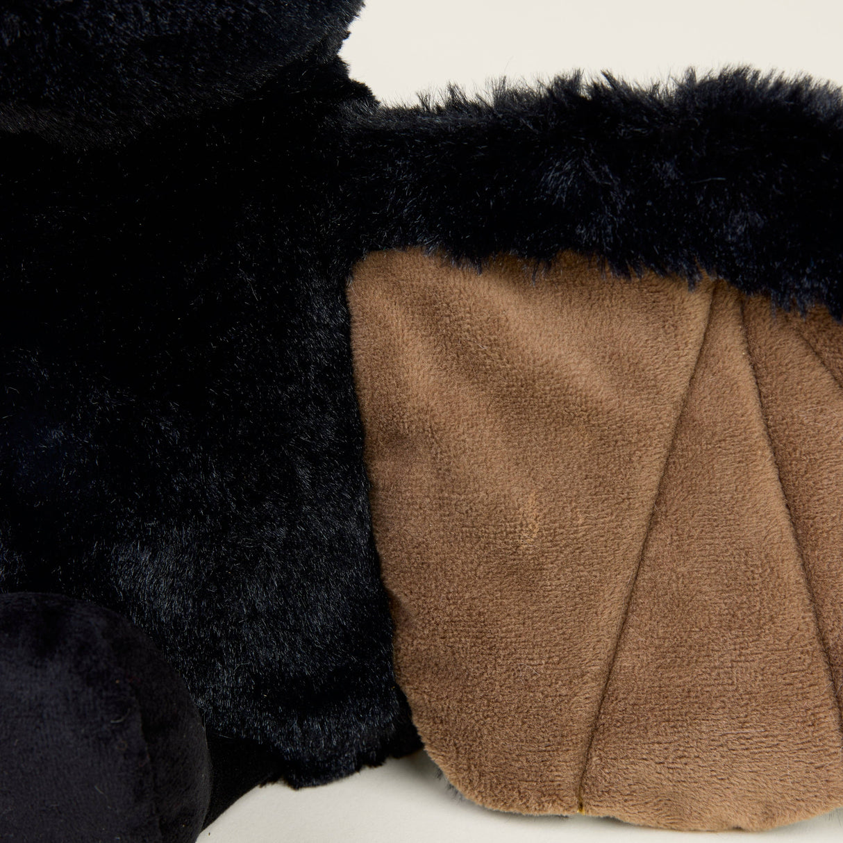 Close-up of soft plush bat wing with black fur and brown fabric details for warmth and comfort.