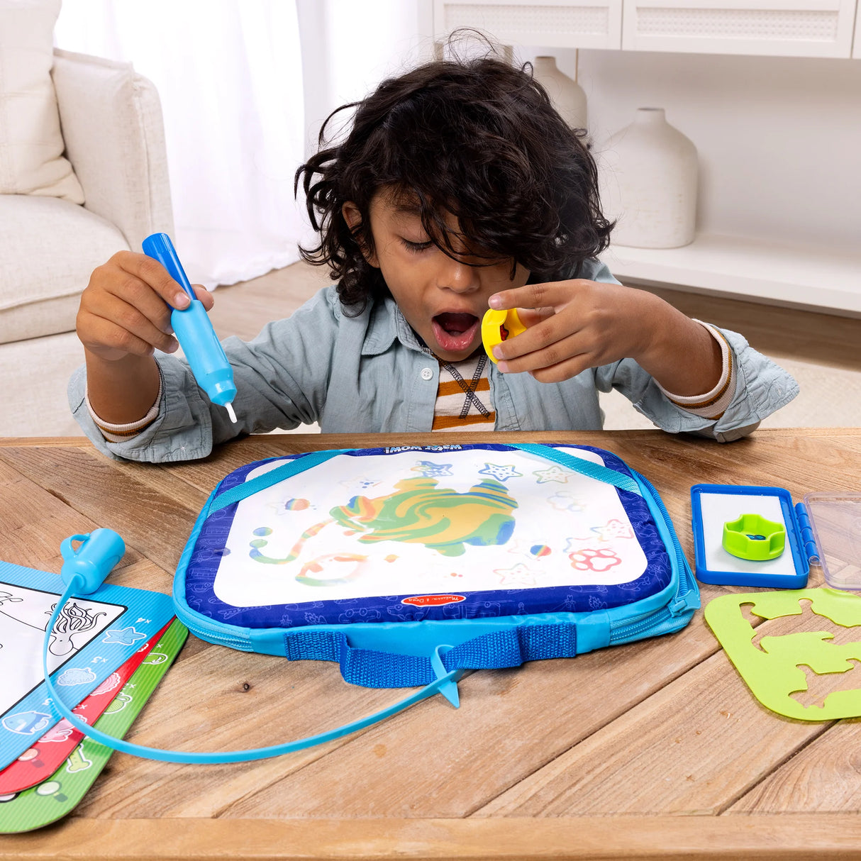 Child using a Water WOW! drawing set with colorful water-reveal board and activity cards on wooden table