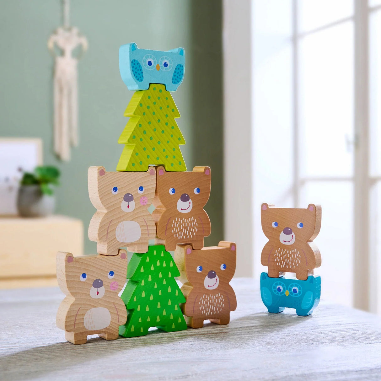 Forest Friends Stacking Toy showing wooden bears, owls, and trees stacked on a table in natural light.