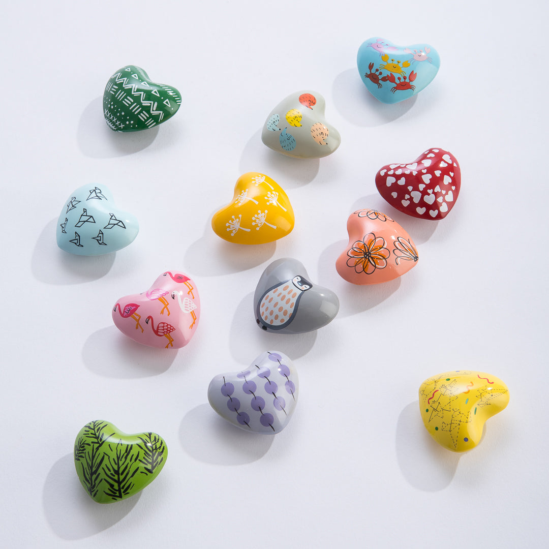 Colorful assorted hand-painted Chime Heart decorations featuring animals, flowers, and geometric shapes for ages 3 and up.