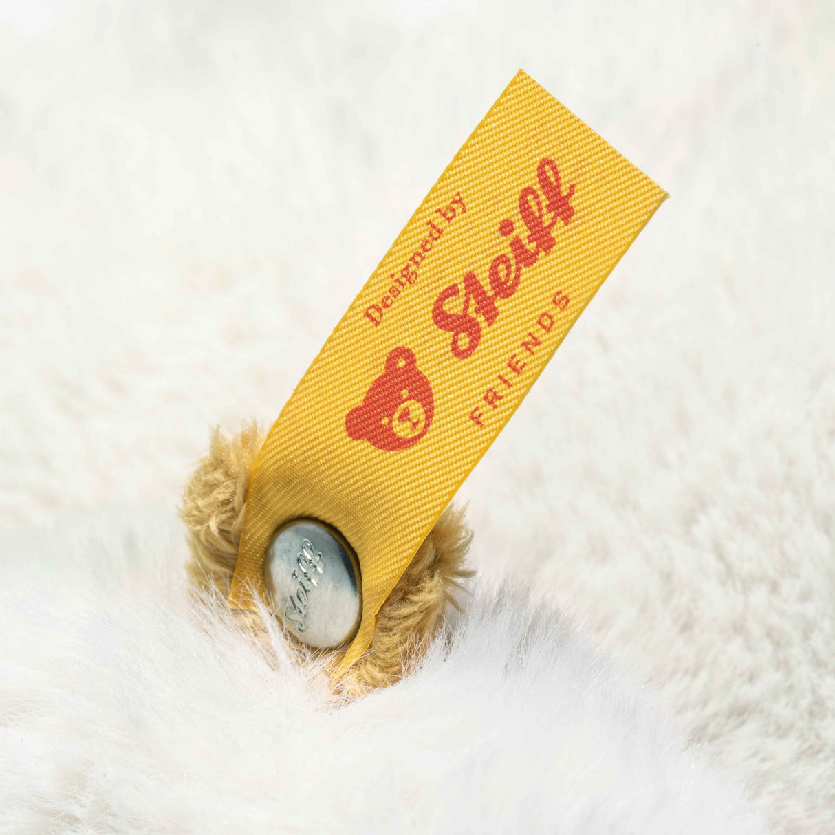 Close-up of the yellow Stoff Friends tag on the plush Goose Gilda Large showing fabric texture and branding details.