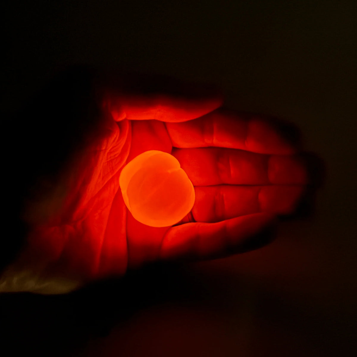 Gootonium: Glowing Orange Solar Putty glowing in a hand in the dark