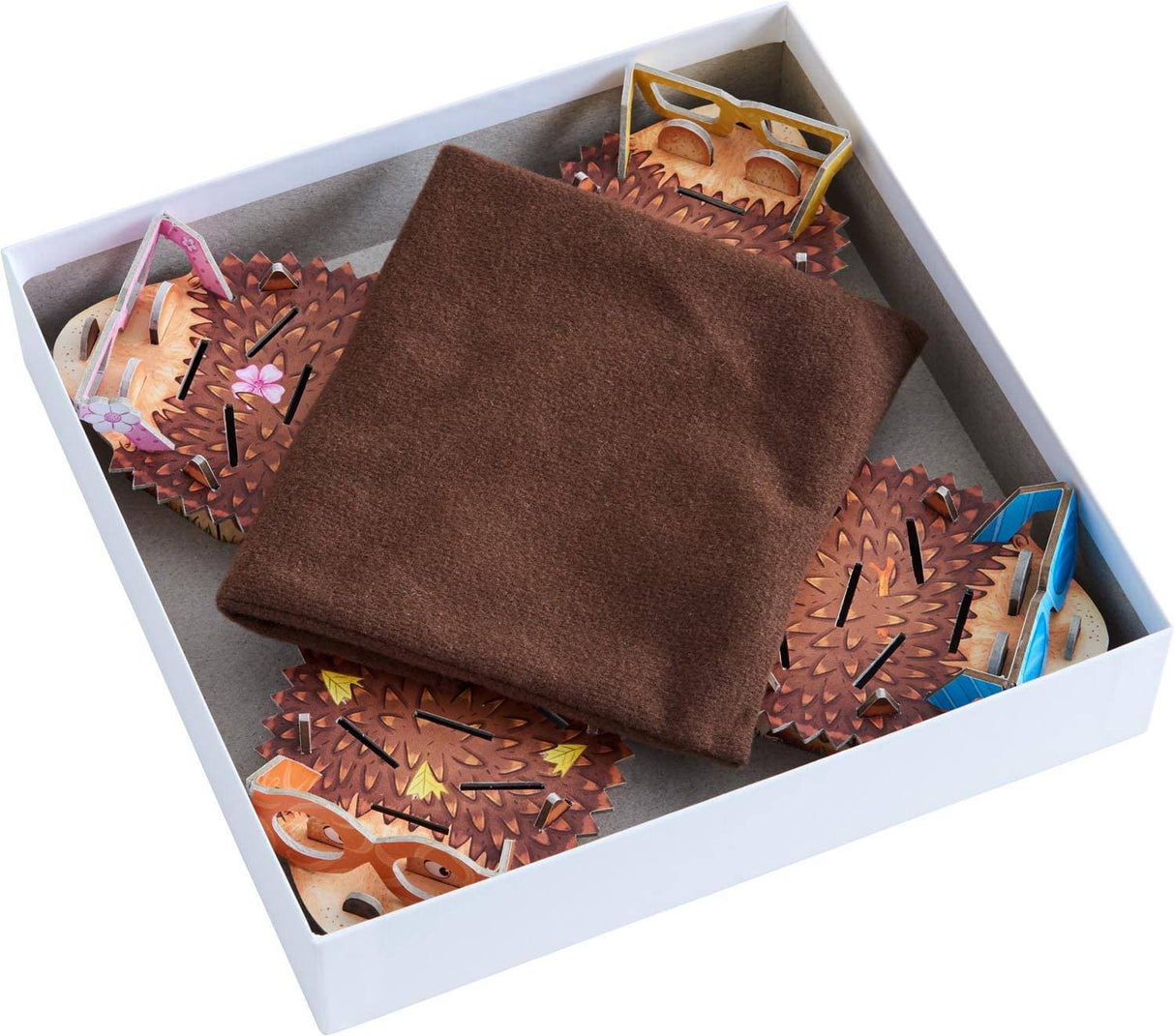 Open box showing colorful hedgehog game pieces with paper spines and a brown cloth bag inside.