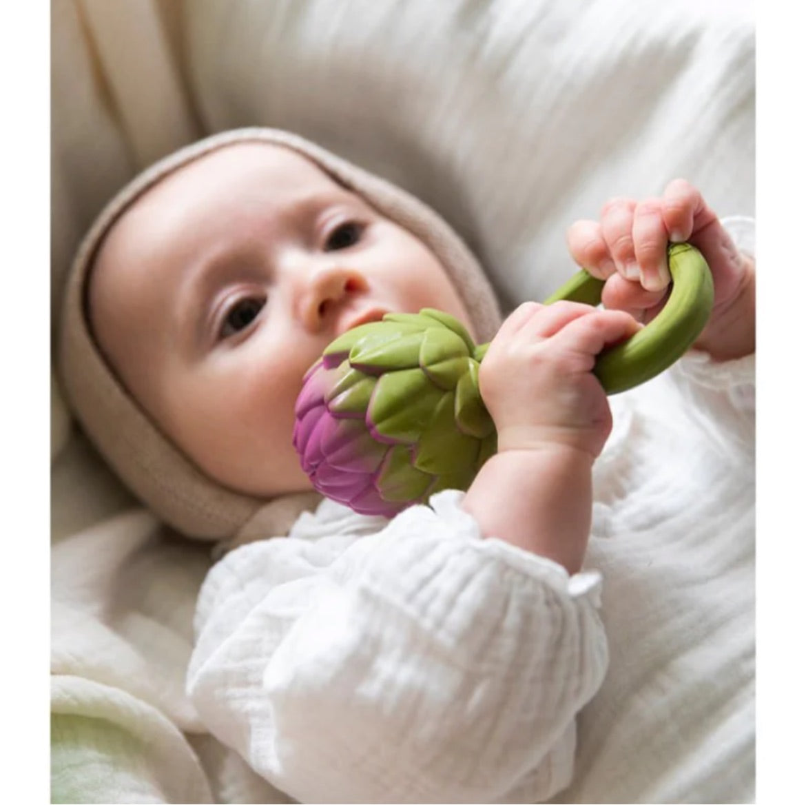 Baby holding and chewing on a green and purple Rattle Toy | Artichoke designed to calm and stimulate senses.