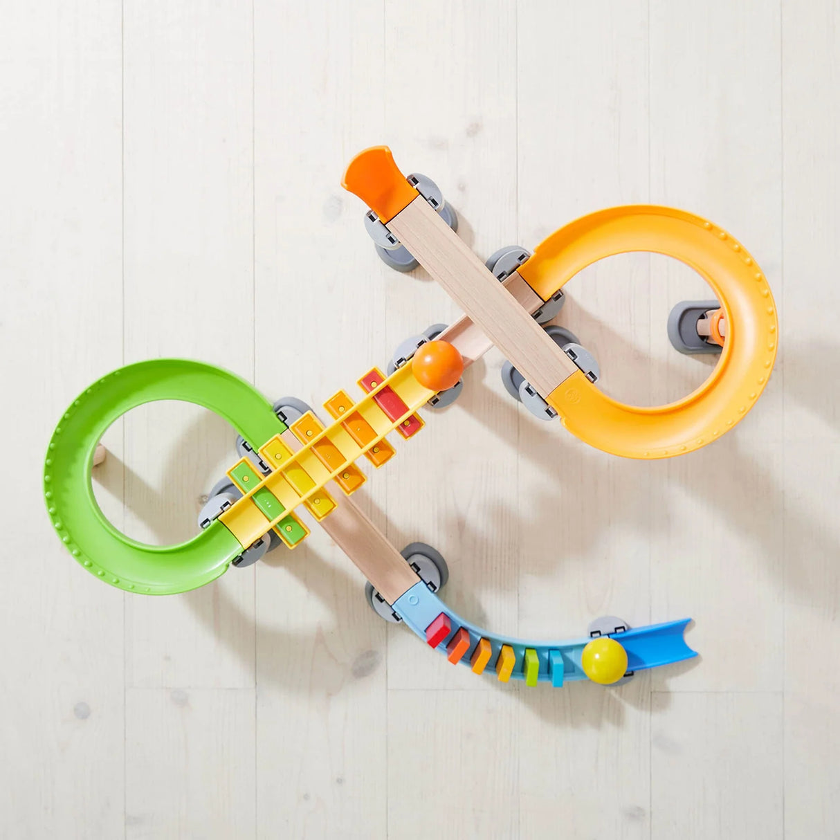 Top view of Kullerbu Melody Domino Set with colorful tracks, wooden balls, and musical jingle sound staircase on wooden floor.