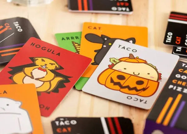 Taco Cat Goat Cheese Pizza Halloween Special Edition cards featuring festive Halloween-themed characters spread on a table.
