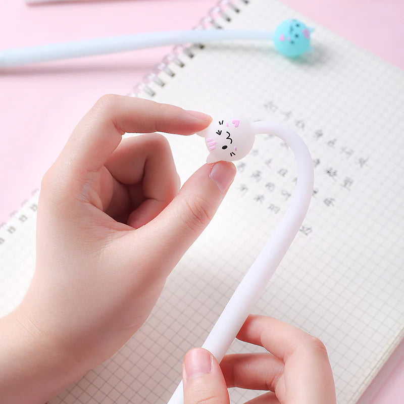 Sweet Cat Wiggle Gel Pen held by hands over a notebook with cute cat-shaped pen toppers in assorted styles.