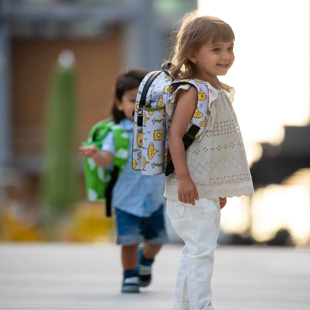 Backpack Toddler Packie | Bunnies worn by smiling toddler outdoors, featuring waterproof laminated fabric and fun bunny design.