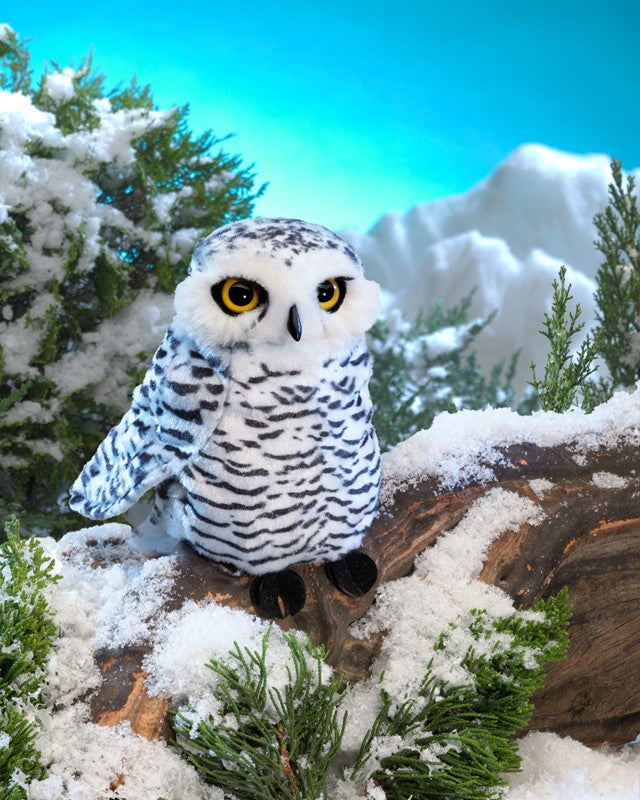 Small Snowy Owl puppet with large eyes and soft printed fabric perched on snowy log in a winter scene.